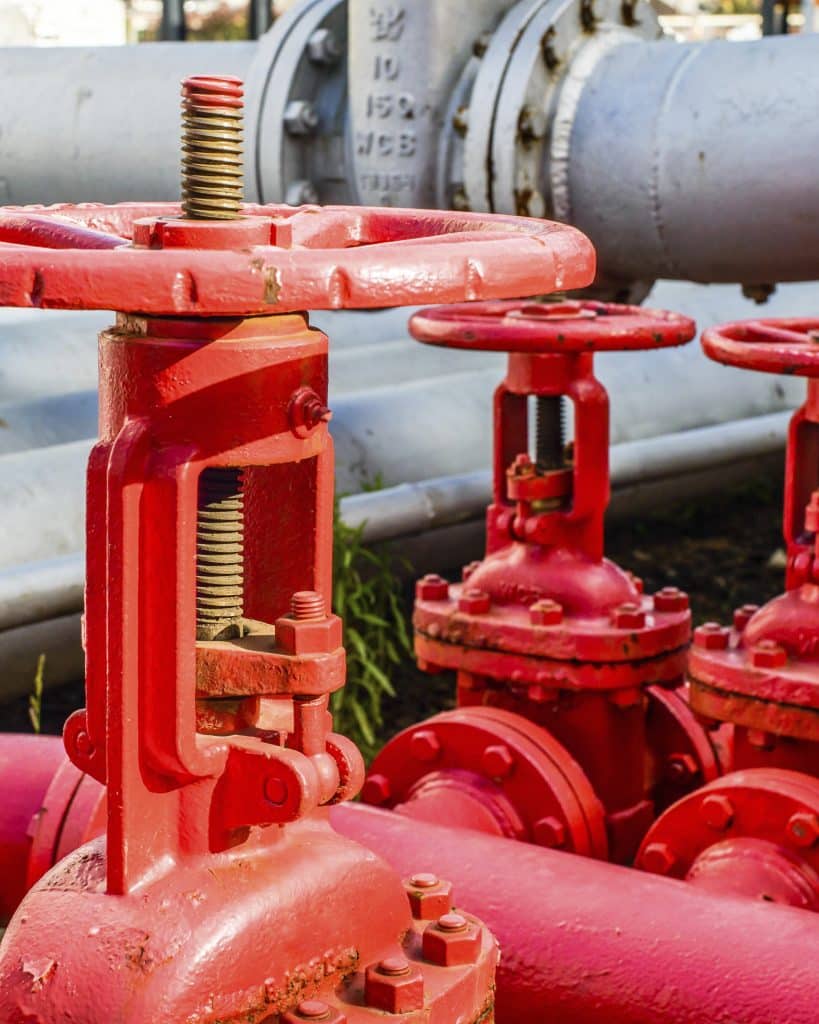 Close up of red industrial pipes and valves at biofuel industrial plant Close up of red industrial pipes and valves at biofuel industrial plant